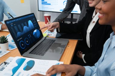 Çok ırklı analist ekibi toplantı masasındaki finansal verileri analiz etmek için BI Fintech yazılımı kullanıyor. Finansal konsol veri ekranında pazarlama göstergesi için analiz edilmiş grafikle birlikte. Uyum