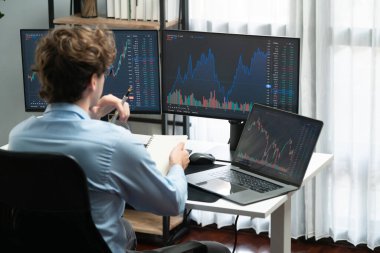 Piyasa stoku grafiği üzerinde çalışan genç profesyonel tüccar ev ofisindeki gerçek zamanlı ekranlara yatırım yaparak önemli döviz kuru kavramları yazarak analiz ediyor. Toplayıcı.