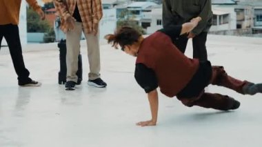 Çatıda çok kültürlü arkadaşlar varken profesyonel İspanyol break dansçısı B boy dansı. Genç modern dans grubu hip hop hareketi yapıyor. Tarz, moda, aksiyon. Açık hava sporu 2024 hiphop..