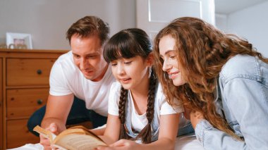 Çocukluk hikayeleri anlatan uyku zamanı, anne ve baba rahat ve rahat yatak odasındaki küçük kızlarına birlikte fantezi kitabı okuyorlar. Modern aile eğlencesi. Eşzamanlama