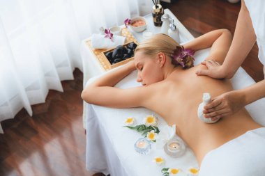 Sıcak bitkisel top spa masaj vücut tedavisi, masör kadın vücuduna nazikçe şifalı bitki torbası bastırıyor. Aromaterapi dinlenme sükuneti ve sükuneti kaplıca salonundaki atmosferi aydınlatıyor. Sessiz.