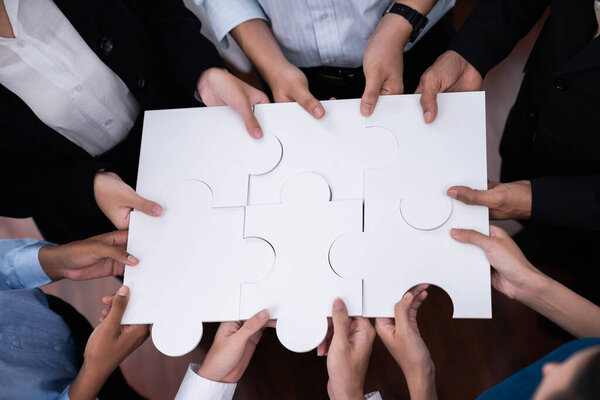 Различные сотрудники корпорации сотрудничают в офисе, соединяя части головоломки, чтобы представлять партнерство и командную работу. Единство и синергия в бизнес-концепции путем слияния головоломки. Конкорд