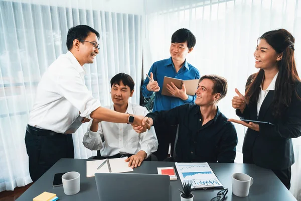 Diverse group of office employee worker shake hand after making agreement on strategic business marketing meeting. Teamwork and positive attitude create productive and supportive workplace. Prudent