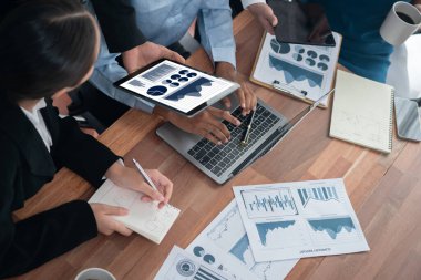 Çok ırklı analist ekibi toplantı masasındaki finansal verileri analiz etmek için BI Fintech yazılımı kullanıyor. Finansal konsol veri ekranında pazarlama göstergesi için analiz edilmiş grafikle birlikte. Uyum