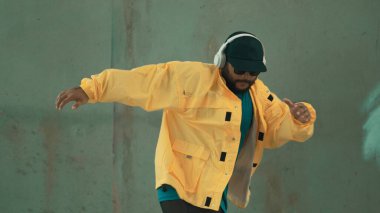 Hippi sokak, şehir merkezinde ayak izleri gösteriyor ya da pratik yapıyor. Hareketli genç break dansçı hareketi ve kol ve bacak esneme hareketi. Açık hava sporu 2024. Gri arka plan. Hip hop modası. ÇalışmaComment.