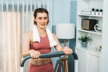 Spor ve atletik bir kadın, evdeki fiziğe ve sağlıklı spor yaşam tarzına uygun vücut egzersizi sırasında koşu bandında koşuyor. Gaiety evde egzersiz eğitimi.