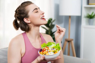 Spor giyimli sağlıklı ve vejetaryen bir kadın bir kase meyve ve sebzeyle. Sağlıklı beslenme ve spor için vejetaryen yaşam tarzı ev konseptinde vücut fiziği.