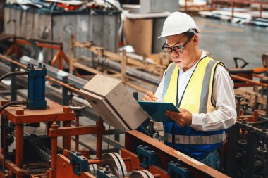 Fabrika mühendisi endüstriyel çelik oluşum makinesini teftiş ediyor. Metal makine mühendisliği denetim denetçisi olarak liderliği gösteriyor..