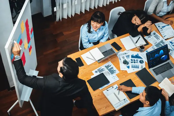 Productive boss or manager demonstrate strong commitment to effective business management on meeting room with diverse race employee, plan and discuss business marketing on meeting table. Meticulous