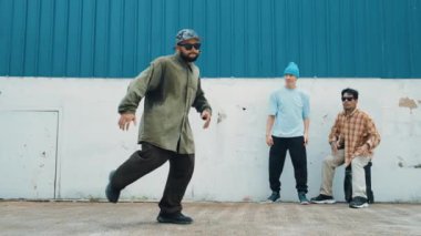 Çok kültürlü arkadaşlar onu cesaretlendirirken, yetenekli hippi araba tekerleği yapıyor. Hip-hop dansçısı, sokak yakınlarındaki bir grup hippi tarafından çevrelenmiş bir şekilde müziğe doğru adım atıyor. Açık hava sporu 2024 hiphop..