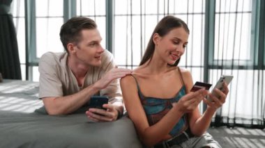 Genç çift, online ödeme uygulaması ve dijital cüzdanı kullanarak kredi kartıyla ödeme yaptıktan sonra mutlu ve heyecanlı hissediyorlar. Mobil internet üzerinden alışveriş ve modern alımlar. Düzenle