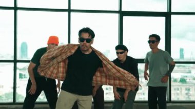 Profesyonel hipster, çeşitli çok kültürlü arkadaşlarıyla birlikte adım atıp dans ediyor. Gökyüzü dövüşçüsü ve şehir manzaralı pencerenin yanında duruyor. Break dans. Açık hava sporları konsepti 2024 hiphop..