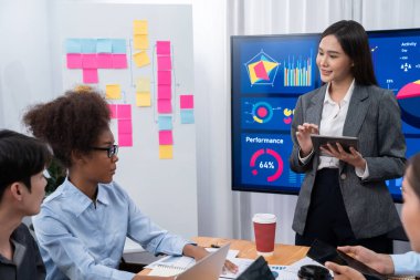 Genç Asyalı iş kadını modern toplantıda TV ekranında veri analizi paneli sunuyor. Bir grup iş adamıyla konferans odasında iş sunumu. Uyum