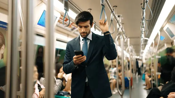 Trende insanlarla çevrili dururken telefona bakan profesyonel bir iş adamı. Kafkas proje yöneticisi e-postaları kontrol ediyor, arka planı bulanık pazarlama stratejisi planlıyor. Sevinçli..