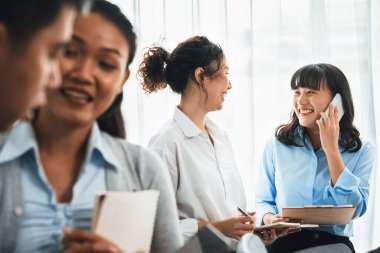 Gülümseyen Asyalı ofis çalışanı arkadaş canlısı ofis ortamında birlikte çalışıyor. İş yerinde, üretken bir ekip çalışması ve paylaşım fikri olan bir grup mutlu iş adamı. Çok titiz.