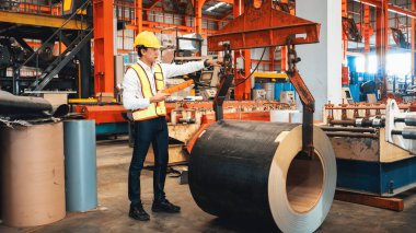 Makine operatörü çelik üretim makinelerini ustalıkla çalıştırıyor, metal fabrikasındaki ağır inşaat mühendisliği malzemeleri için silindir rulo çelik üretiyor. Örnek gösteriliyor