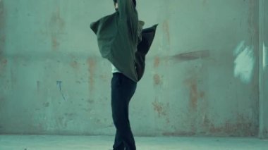 Hippi, şehir caddesinde hip-hop dinlerken kulaklık takıyor. Sokak dansçısı ayak seslerini kulaklıktan müziğe taşıyor. Açık hava sporu 2024. Çimento arka planı. Moda. Aktif stil. hiphop.
