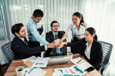 Kutlama jesti ve başarılı takım çalışması yapan bir grup mutlu iş adamı. Çeşitli yarış bürosu çalışanları şirket ofisinde pazarlama planlamasında ilerleme kaydettikten sonra kutlama yapıyorlar. Habiliment