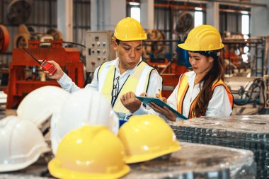 Fabrika ustabaşı ve mühendis çelik makinesi ve ağır endüstriyel malzeme kalitesinde ürün teftişi yapıyor. Makine güvenliği ve kalite kontrollü metal levha üretimi. Örnek gösteriliyor