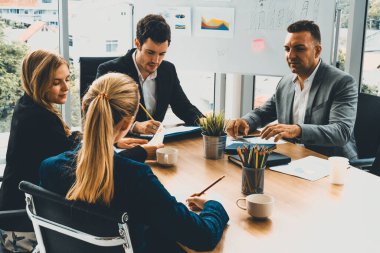 İş adamı yönetici, diğer iş adamları ve iş kadınlarıyla modern ofiste kahve fincanları ve belgelerle grup toplantısı yapıyor. Şirket çalışanlarının ortak çalışma konsepti. uds