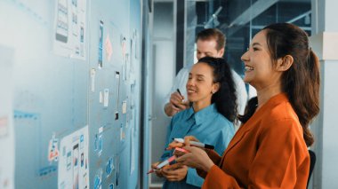 Bir grup iş adamının cam tahtaya yapışkan notlar yapıştırması. Profesyonel iş adamları pazarlama stratejisi geliştirirken cam duvara notlar yapıştırıyor. İş toplantısı. Yönlendirici.