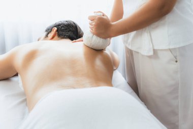 Sıcak bitkisel top spa masaj vücut tedavisi, masör erkek vücuduna nazikçe şifalı bitki torbası bastırıyor. Aromaterapi dinlenme sükuneti ve sükuneti kaplıca salonundaki atmosferi aydınlatıyor. Sessiz.