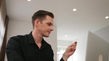Genç adam internet bankacılığı için kredi kartlı dizüstü bilgisayar kullanıyor. İnternet üzerinden alışveriş yapıyor. Banka kartıyla modern ve kullanışlı online satın alma. Düzenle
