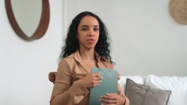 Klinikteki dost canlısı psikolog kadın. Profesyonel portresi, gülümsemesi ve hasta psikoloğunu ziyaret etmesi için elinde bir dosya tutuyor. Deneyimli ve kendinden emin psikolog çok önemli bir uzmandır.