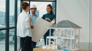 Profesyonel mimar mühendis ekibi konuşuyor, paylaşıyor, tasarım hakkında beyin fırtınası yapıyor. Yönetici planı dinlerken genç mimar plan yapıyor. İzleme