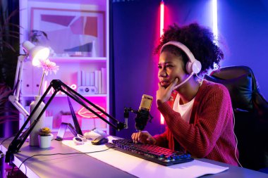Afro-Amerikalı kız flaması, neon odada kulaklık takarak Esport yetenekli takımıyla online dövüş yaparken hayal kırıklığına uğradı. Rakiplerini kazanmak için strateji planlayan diğer oyuncularla konuşmak. Tatlandırıcı.