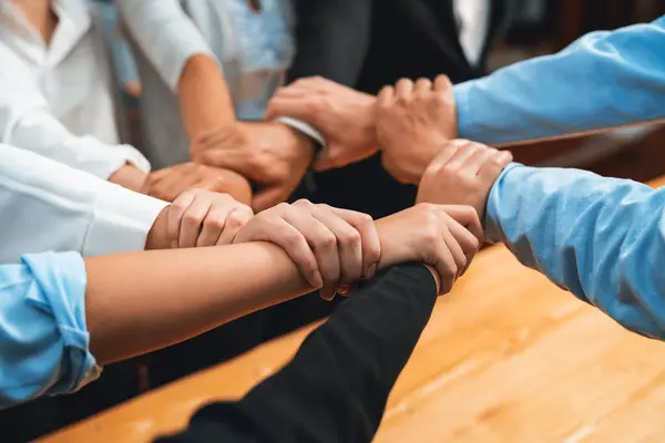 Multicultural business people holding hand together in circle. Unity teamwork in office business workplace. Diverse ethnic office worker engaged in team building. Meticulous