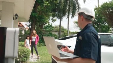 Evde EV şarj istasyonu kurulumu üzerinde çalışan nitelikli teknisyen, EV için dizüstü bilgisayarla şarj sisteminde sorun çıkarma ve yapılandırma ayarları yapıyor. Titiz