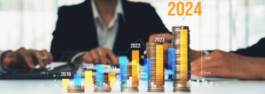 Büyüyen madeni para yığını iş yatırımını ve ekonomik büyümeyi simgeliyor. Finansal hedefe ulaşmak ve 2024 yılına maksimum kar sağlamak için finansal planlama yapan iş adamları. Kurnaz.