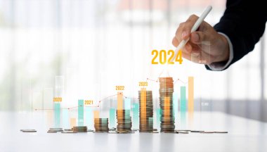 Büyüyen madeni para yığını iş yatırımını ve ekonomik büyümeyi simgeliyor. Finansal hedefe ulaşmak ve 2024 yılına maksimum kar sağlamak için finansal planlama yapan iş adamları. Kurnaz.
