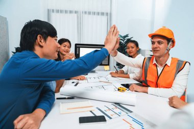 Çeşitli inşaat mühendisi ve müvekkil grupları, mimari proje üzerinde başarılı bir anlaşma yaptıktan, inşaat planını gözden geçirdikten ve toplantı masasında plan oluşturduktan sonra kutlama ve beşlik çakışma yaptılar.