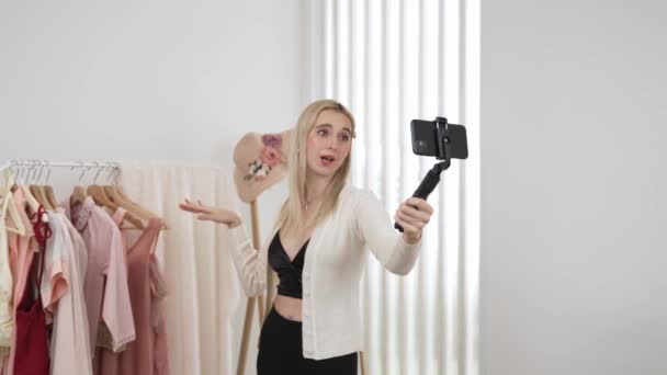 年轻的社交媒体内容创建者女人用自拍棒制作时尚视频 在制作有说服力的在线服装的同时 博客对着相机微笑 向观众或追随者推销Vlog — 图库视频影像
