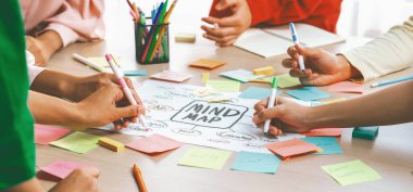 Yaratıcı iş adamları, zihin haritalama kullanarak pazarlama stratejisi ve iş planı hakkında beyin fırtınası yapıyorlar. Girişim ekibi kağıda yazmak için birlikte çalışır. Eline odaklan. - Yakın çekim. Değiştirilmiş.