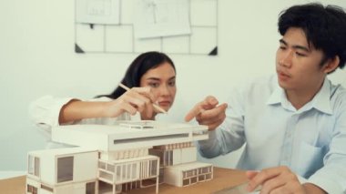 Profesyonel akıllı iş birliği mühendisi mühendis ekibi modern ofisteki ev yapısını planla kontrol ederken genç ve güzel proje yöneticisi not alıyor. Yaratıcı tasarım konsepti. Tertemiz...