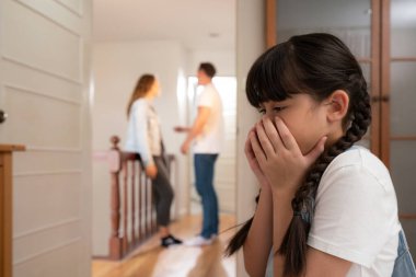 Stresli ve mutsuz genç kız, arka planda ebeveynleri tartışırken yüzünü kapatıyor. Evde aile içi şiddet ve travmatik çocukluk depresyona dönüşür. Eşzamanlama