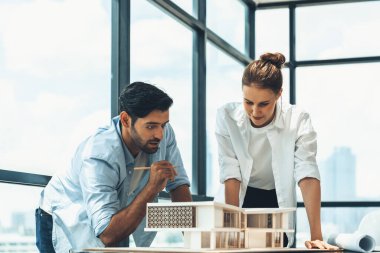 Akıllı beyaz mimar mühendis takımı ev modelini ölçmek için birlikte çalışıyor. Bir grup profesyonel iç mimar tasarım inşaatı hakkında fikir paylaşımı ve beyin fırtınası yapıyor. İzleme.