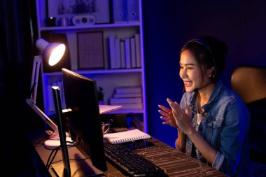 Sunucu kanalı Asyalı etkileyicisi canlı yayında konuşuyor. Sosyal medyada kulaklık takıyor, bilgisayar kaydı yapıyor, dinleyicileri selamlıyor ve Neon Modern Stüdyoları 'nda online olarak koçluk yapıyor. Taktik.