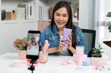 Genç ve güzel Asyalı bir kız nemlendirici vücut kremi ürününü inceleyerek sosyal medyada canlı cilt testi yaparak modern odada en çok satanlarla canlı telefon kaydı yapıyor. Taktik.
