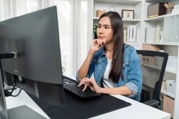 在社交媒体频道上 工作的年轻漂亮的亚裔创意经理用键盘在Pc上搜寻网页设计 并在现代家庭办公室里穿上蓝色牛仔裤衬衫 Stratagem — 图库照片