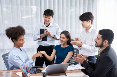 Çeşitli iş arkadaşları başarıyı şirket işyerindeki el sıkışma ve takım çalışmasıyla kutluyor. Çok kültürlü, mutlu profesyonellerden oluşan bir ekip ofiste tokalaşarak birlik oldular. Uyum