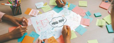 Profesyonel başlangıç grubu zihin haritası kullanarak yaratıcı pazarlama fikrini paylaşıyor. Genç yetenekli iş adamları yapışkan notlar yazarken beyin fırtınası planı yapıyorlar. Eline odaklan. - Yakın çekim. Değiştirilmiş.