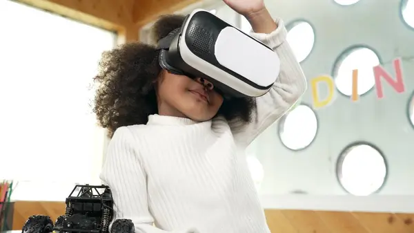 stock image Creative girl wearing VR headset to learning in metaverse. Funny kid enjoy to wearing AI headset and enter to virtual world program in STEM technology class. Innovation. Future lifestyle. Erudition.