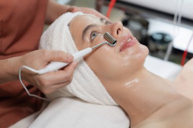 Güzeller güzeli beyaz kadın güzellik teçhizatı ve tıbbi ekipmanlarla çevrili modern kaplıca salonundaki profesyonel eller tarafından masaj yaptırırken spa yatağında uzanıyor. Kapatın. Huzur