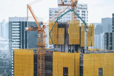 Dış gökdelenlerin, kule vinçleri olan inşaat alanının görüntüsü. İnşaat halindeki şehir manzarası. Binanın tadilatı için çalışan vinçler var. Mavi gökyüzü arka planı. Mimari. Süslü.