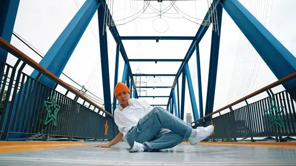 プロのブレイクダンサーが橋でストリートダンスの足跡を行います アジアのヒップスターは フリーズポーズをしている間 ヘッドフォンを着用します ブレイクダンサー ストリートダンサーフリースタイルのコンセプト アウトドアスポーツ 2024 スプライトリー — ストック写真