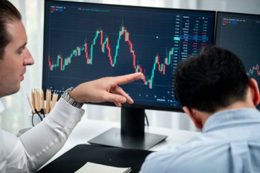 Yatırımcı hisse senedi işçisi, dinamik döviz kuru veritabanı grafiğindeki yatırım eğilimini monitör ekranı ile analiz ediyor. Mevcut durum krizinde bilgi paylaşımı kar ve zarar. Satılabilir.